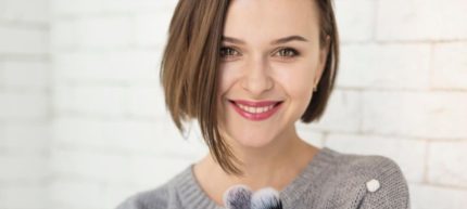 Smiling girl holding makeup brushes